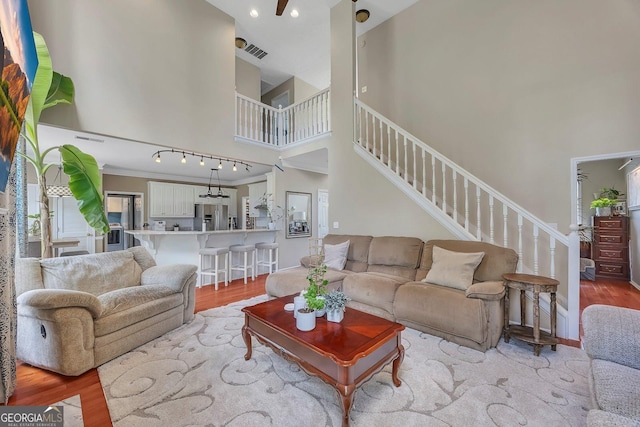 living room with a towering ceiling, light wood finished floors, stairway, recessed lighting, and baseboards
