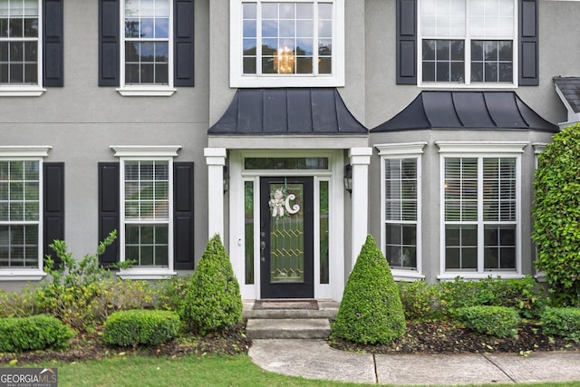 doorway to property with a standing seam roof, stucco siding, and metal roof