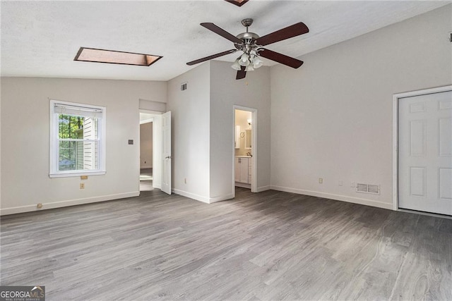 unfurnished bedroom with lofted ceiling, wood finished floors, baseboards, and connected bathroom