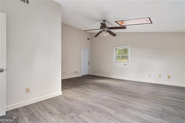 empty room featuring ceiling fan, wood finished floors, baseboards, and vaulted ceiling