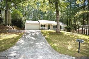 view of front of property with asphalt driveway, an attached garage, a front lawn, and covered porch