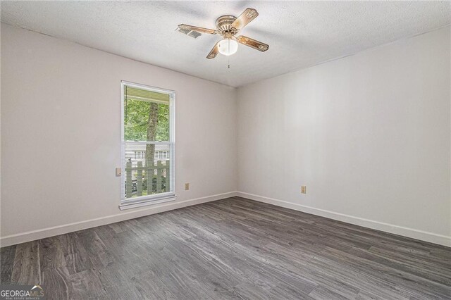 unfurnished room with dark wood finished floors, a ceiling fan, baseboards, and a textured ceiling
