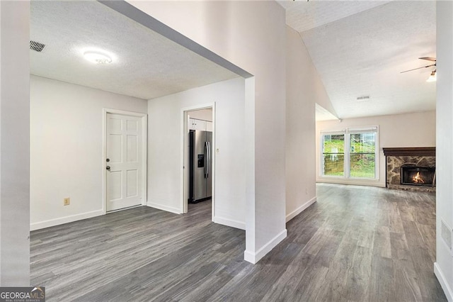 unfurnished living room with a textured ceiling, dark wood-type flooring, baseboards, a ceiling fan, and a fireplace