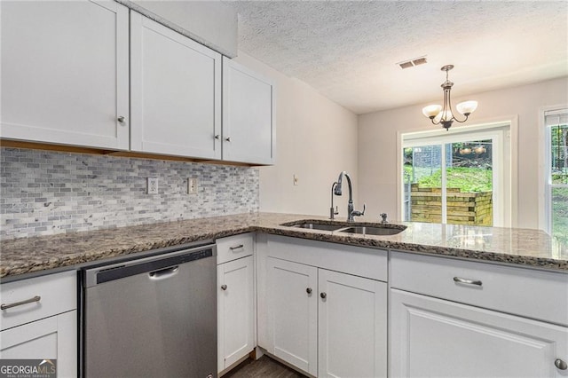 kitchen with stainless steel dishwasher, a sink, white cabinetry, decorative backsplash, and a textured ceiling