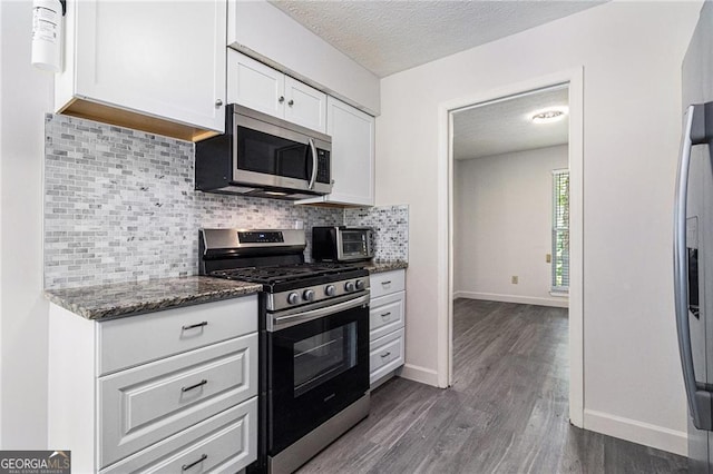 kitchen with appliances with stainless steel finishes, white cabinetry, dark wood-type flooring, a textured ceiling, and backsplash