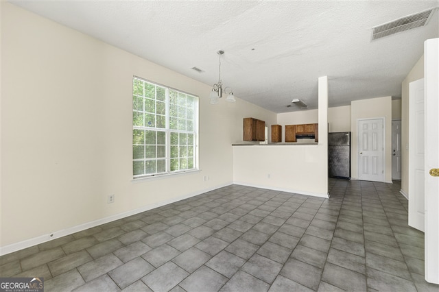 7331 Wagon Wheel Ct, Jonesboro, GA 30236 - unfurnished living room featuring a textured ceiling, baseboards, and a chandelier