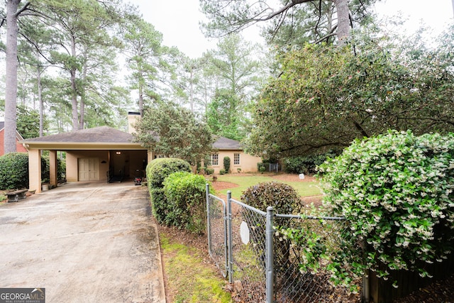 view of front of property featuring fence, a carport, driveway, a gate, and a chimney