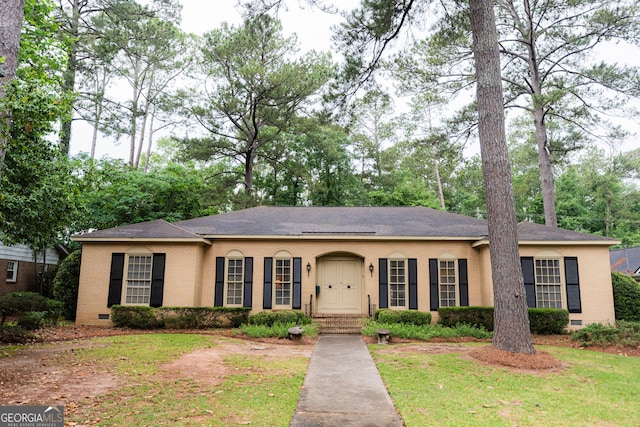 single story home featuring crawl space, brick siding, roof with shingles, and a front yard