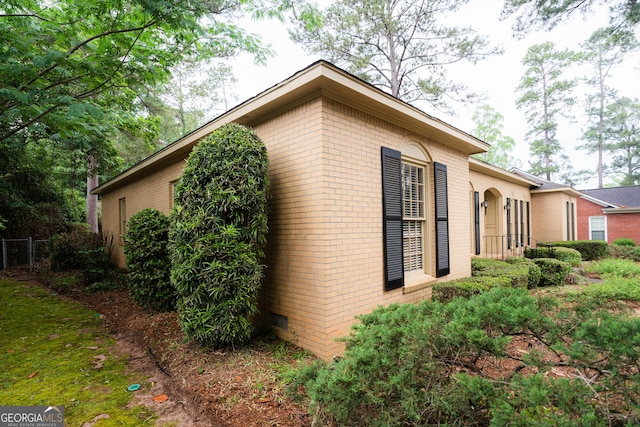 view of side of property with brick siding and fence