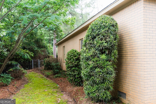 view of property exterior with brick siding, fence, and crawl space