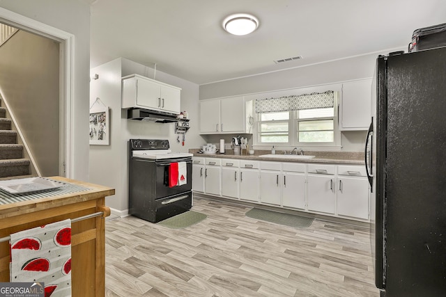 kitchen with range with electric cooktop, freestanding refrigerator, a sink, white cabinetry, and light wood-type flooring