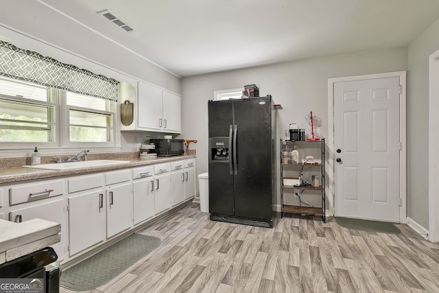 kitchen with black appliances, a sink, light wood-style floors, and plenty of natural light