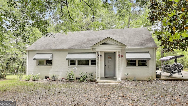 view of front of house featuring brick siding, crawl space, and roof with shingles