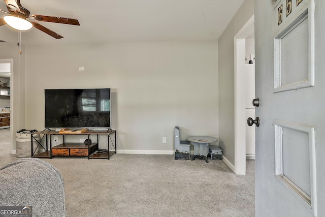 carpeted living area with a ceiling fan and baseboards