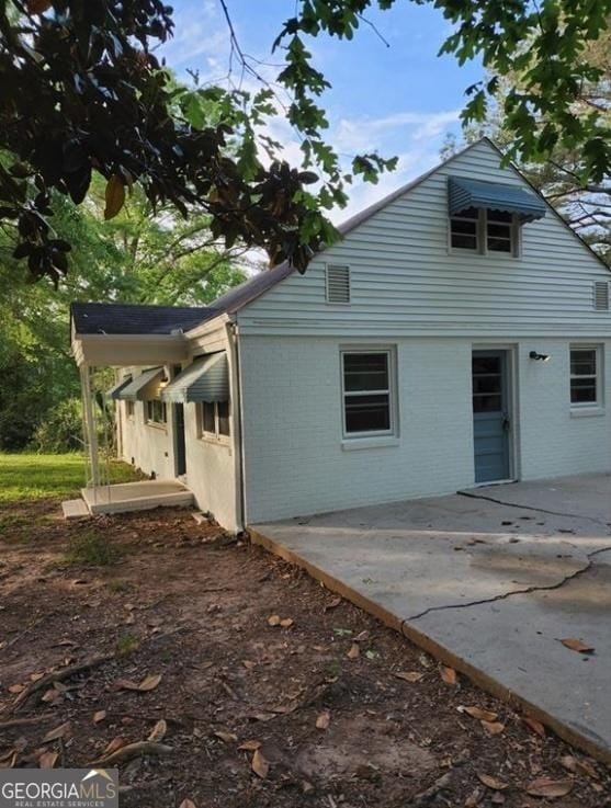 view of side of home featuring brick siding and a patio area