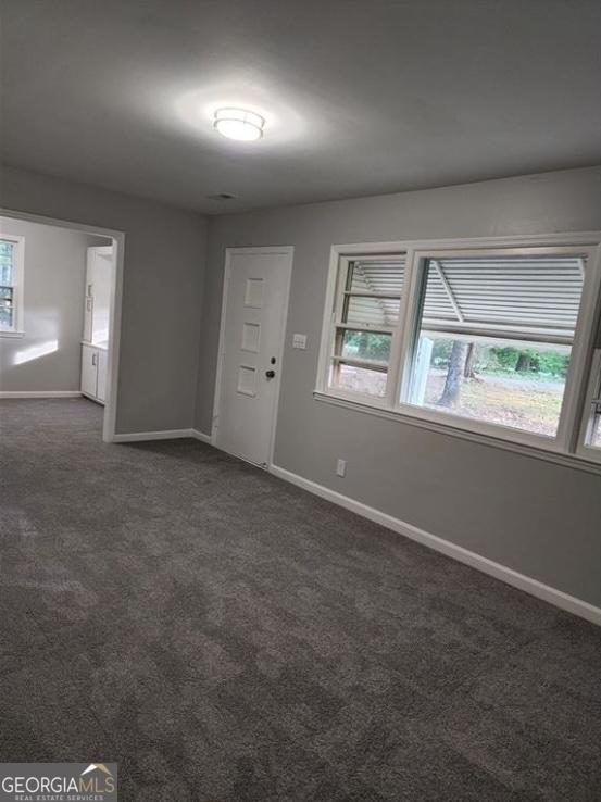 foyer with baseboards and dark carpet