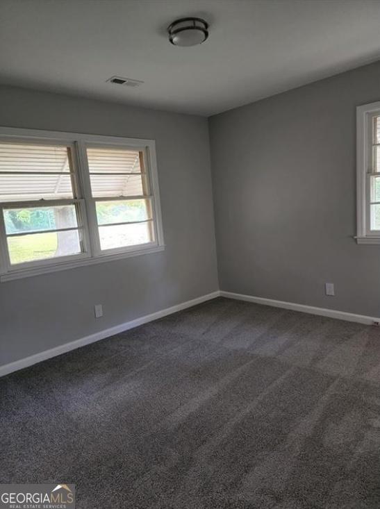 unfurnished room with dark carpet and baseboards