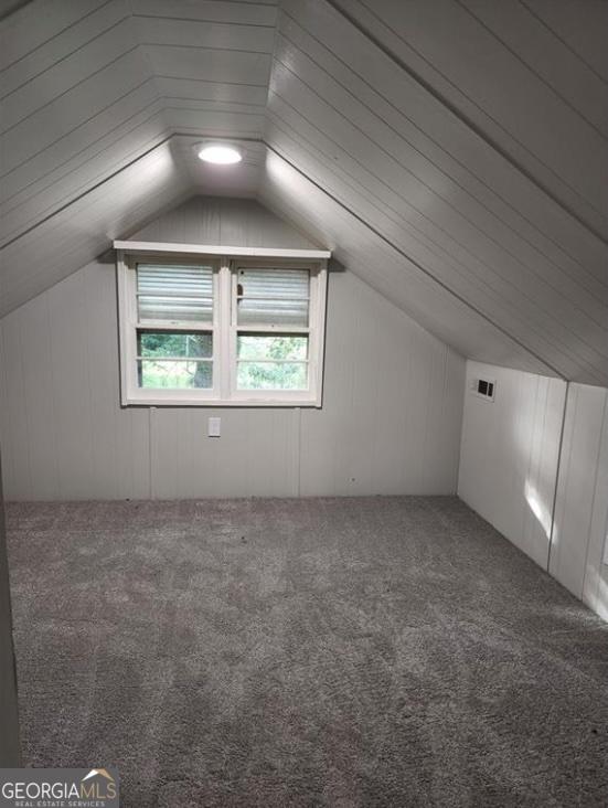 additional living space with carpet flooring and lofted ceiling