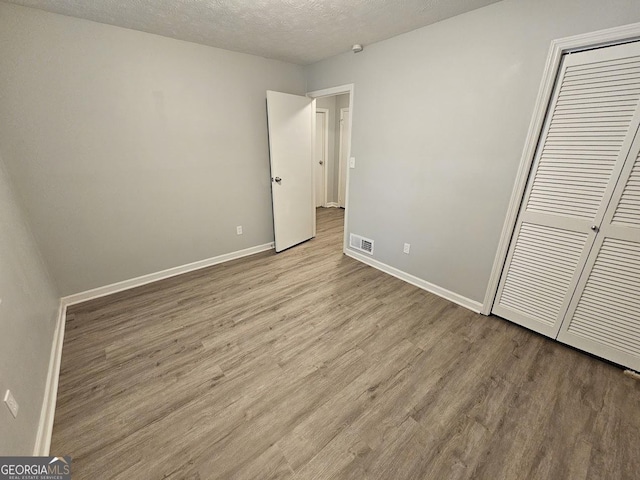 2860 Cocklebur Cove Ct, Decatur, GA 30034 - unfurnished bedroom with wood finished floors, baseboards, a textured ceiling, and a closet