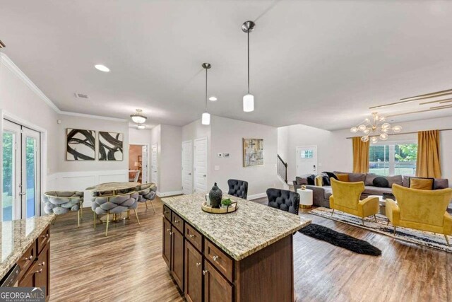 139 Coldwater Ln, Griffin, GA 30224 - kitchen featuring open floor plan, light wood-type flooring, decorative light fixtures, a chandelier, and crown molding