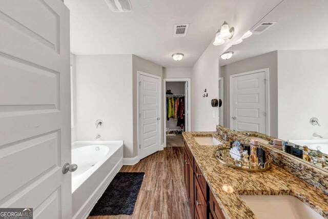 139 Coldwater Ln, Griffin, GA 30224 - bathroom featuring double vanity, a garden tub, wood finished floors, and a spacious closet