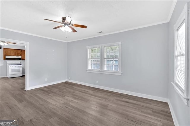 spare room featuring a ceiling fan, dark wood finished floors, baseboards, and crown molding