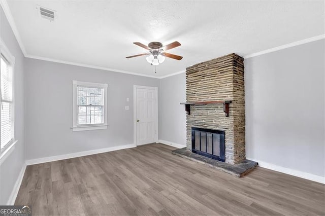 unfurnished living room with a ceiling fan, wood finished floors, a large fireplace, baseboards, and crown molding