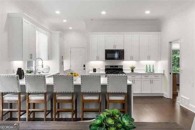 1260 Heards Ferry Rd, Sandy Springs, GA 30328 - kitchen featuring black microwave, stainless steel gas range, a sink, white cabinetry, and ornamental molding