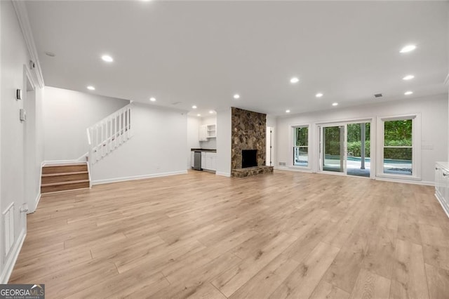 1260 Heards Ferry Rd, Sandy Springs, GA 30328 - unfurnished living room with light wood-style flooring, a stone fireplace, stairs, recessed lighting, and baseboards