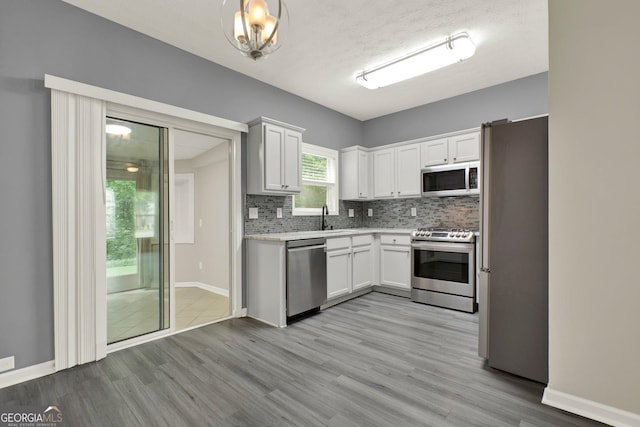 556 Poplar Bnd, Canton, GA 30114 - kitchen with stainless steel appliances, light wood-type flooring, decorative backsplash, a sink, and light countertops