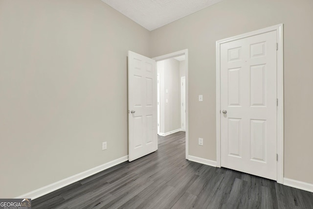 556 Poplar Bnd, Canton, GA 30114 - unfurnished bedroom featuring dark wood-type flooring, baseboards, and a textured ceiling