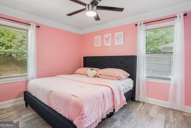 bedroom featuring multiple windows, baseboards, wood finished floors, and crown molding
