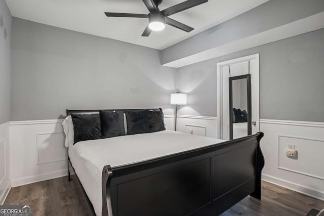 bedroom with wainscoting, dark wood-style floors, and ceiling fan