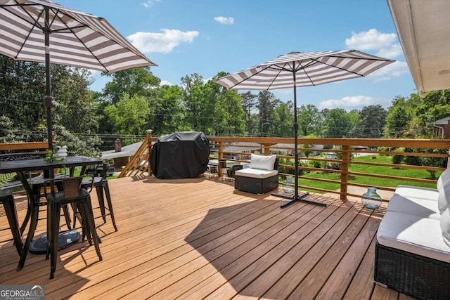 wooden deck with outdoor dining space, area for grilling, and view of scattered trees