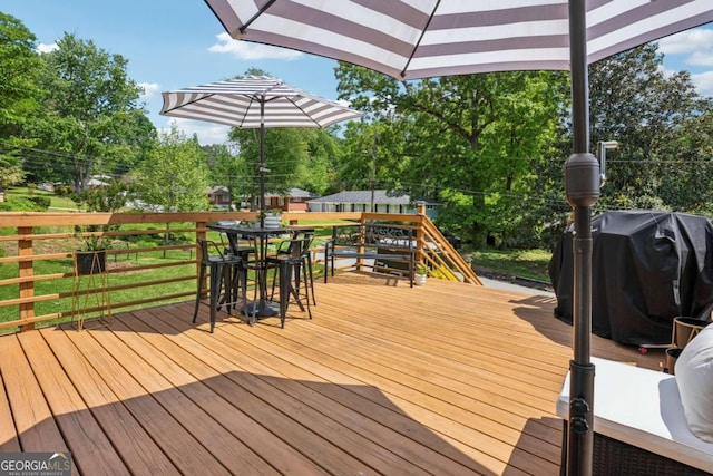 wooden terrace with outdoor dining area, view of scattered trees, and a grill