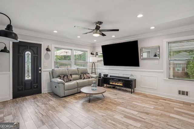 living room featuring a ceiling fan, wood finished floors, a wainscoted wall, ornamental molding, and recessed lighting