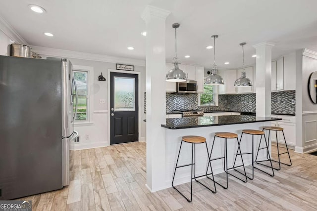 kitchen featuring stainless steel appliances, a breakfast bar area, white cabinetry, backsplash, and crown molding