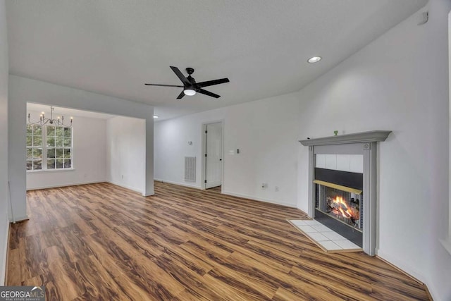 unfurnished living room with a chandelier, a fireplace, wood finished floors, a ceiling fan, and recessed lighting
