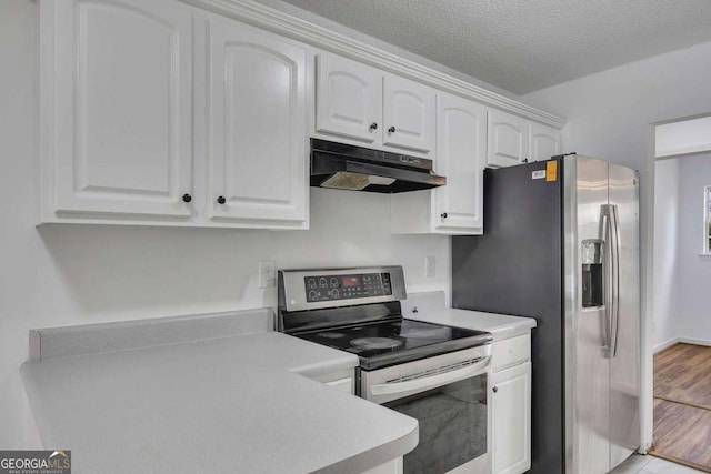 kitchen with appliances with stainless steel finishes, under cabinet range hood, white cabinets, light countertops, and a textured ceiling