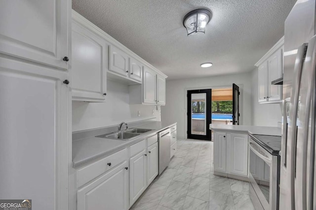 kitchen with stainless steel appliances, a sink, light marble finish flooring, white cabinets, and a textured ceiling