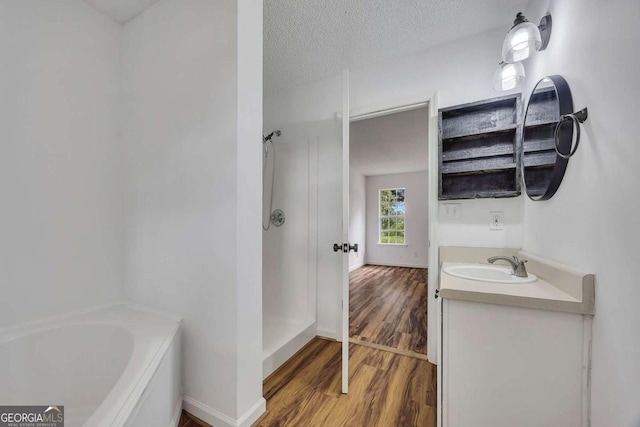 full bath featuring wood finished floors, a shower, vanity, a bathtub, and a textured ceiling