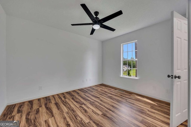 spare room featuring wood finished floors, a ceiling fan, and baseboards