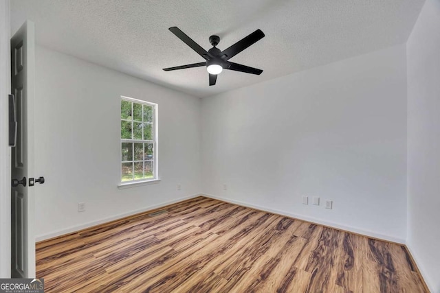 empty room featuring wood finished floors, ceiling fan, a textured ceiling, and baseboards