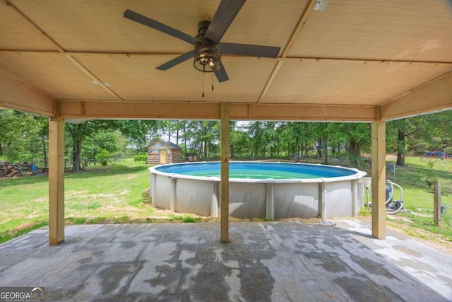swimming pool with a yard, a patio area, and a ceiling fan