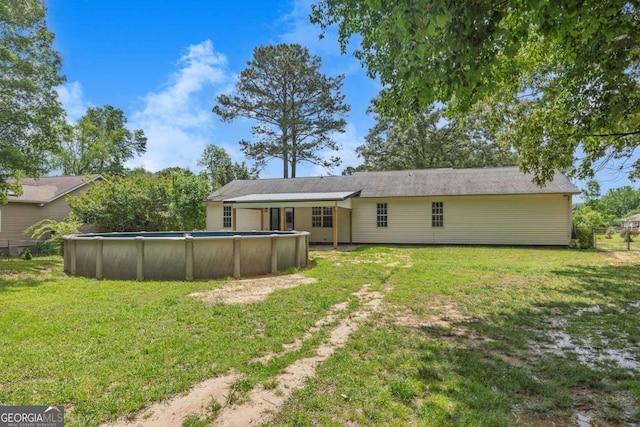 back of house featuring a yard and an outdoor pool