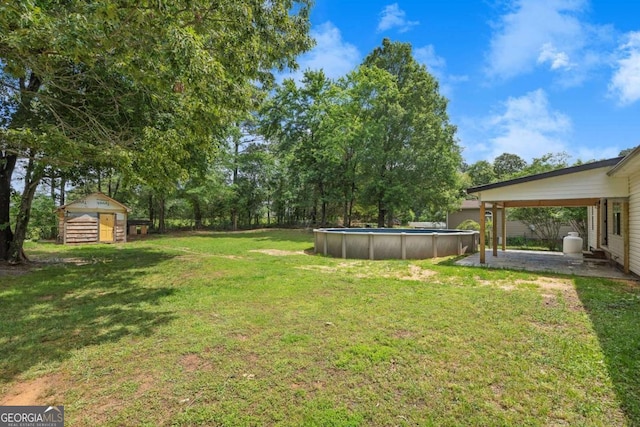 view of green lawn featuring a shed, a patio, an outdoor pool, and an outbuilding