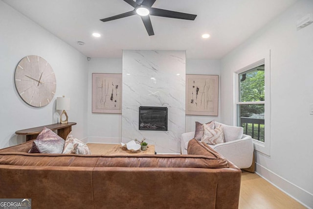 living area featuring wood finished floors, a premium fireplace, baseboards, ceiling fan, and recessed lighting