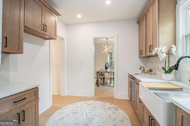 kitchen with light wood-type flooring, recessed lighting, stainless steel dishwasher, a sink, and baseboards