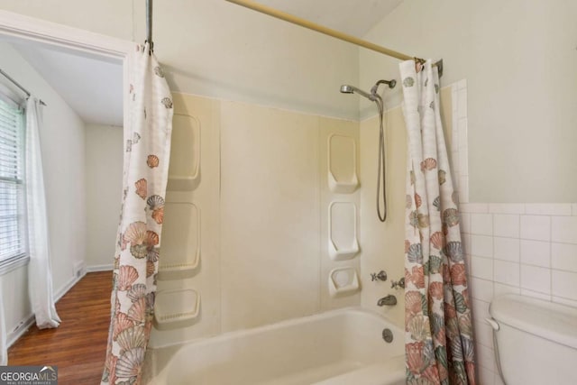 full bath featuring plenty of natural light, tile walls, shower / bath combination with curtain, toilet, and wainscoting