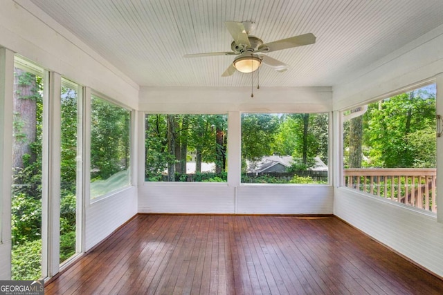 unfurnished sunroom with a ceiling fan, wood-type flooring, and healthy amount of natural light